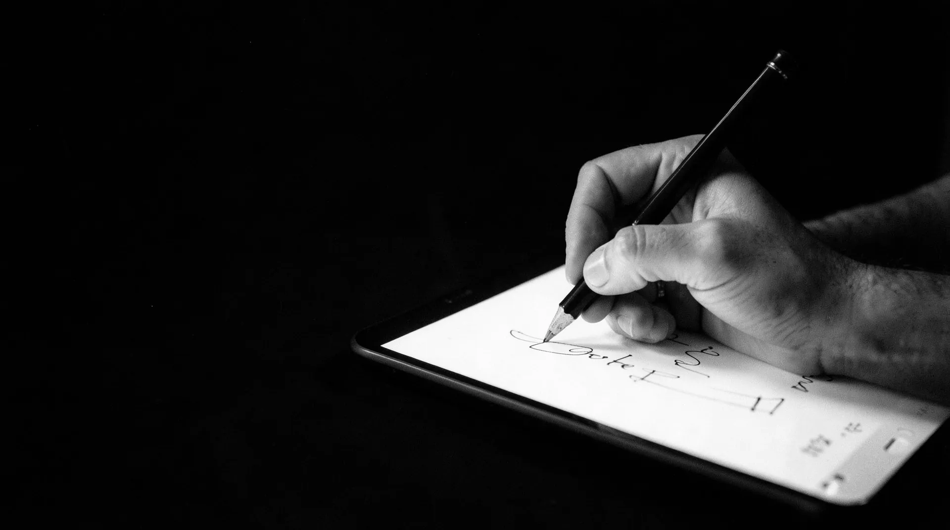 A designer drawing on a tablet with a stylus in a dark studio